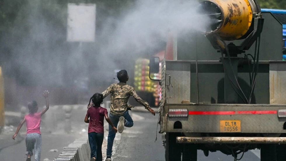 Children run behind a truck spraying water along a street on a hot summer day in New Delhi on May.28.