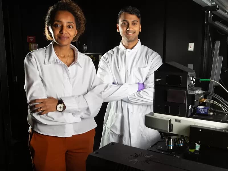 Loza Tadesse and Aditya Garg standing next to a Raman microscope