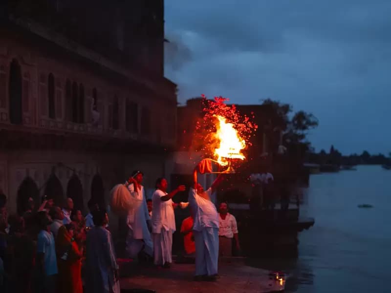 2010 में यमुना नदी में आई बाढ़ के दौरान, वृंदावन में भक्त और साधु अंधेरे में तेल का एक जलता हुआ और कई स्तरों वाला दीपक उठाते हैं।