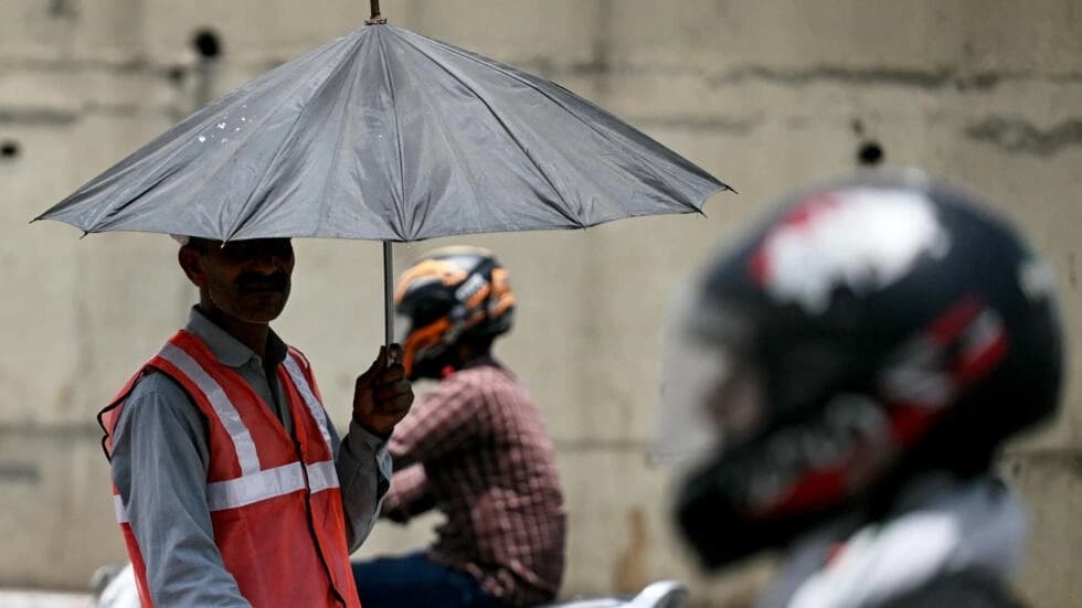 As developing countries urge increases in climate aid, a toll booth worker takes shade under an umbrella during a record heatwave in Delhi.