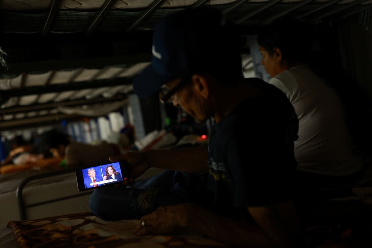 A migrant, seeking to reach the United States and request asylum, watches the presidential debate between the Republican presidential nominee, former U.S. President Donald Trump and the Democratic presidential nominee, U.S. Vice President Kamala Harris, on a mobile phone screen inside the El Buen Samaritano shelter in Ciudad Juarez, Mexico, Sep.10, 2024.