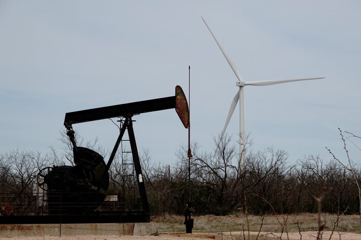 A pump jack drills oil crude from the Yates Oilfield in West Texas’s Permian Basin, as a 1.5MW GE wind turbine from the Desert Sky Wind Farm is seen in the distance, near Iraan, Texas, U.S., Mar.17, 2023.