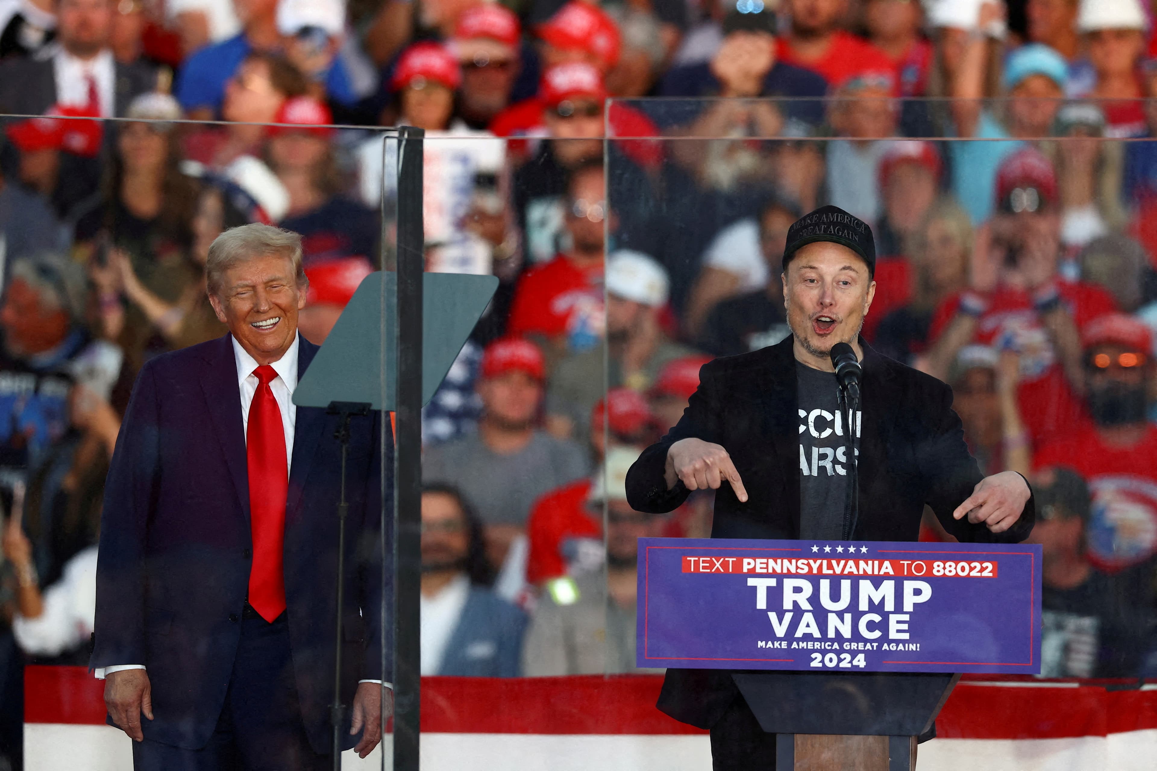 Tesla CEO and X owner Elon Musk speaks as Republican presidential nominee and former U.S. president Donald Trump reacts during a rally at the site of the July assassination attempt against Trump, in Butler, Pennsylvania, U.S., October 5, 2024.