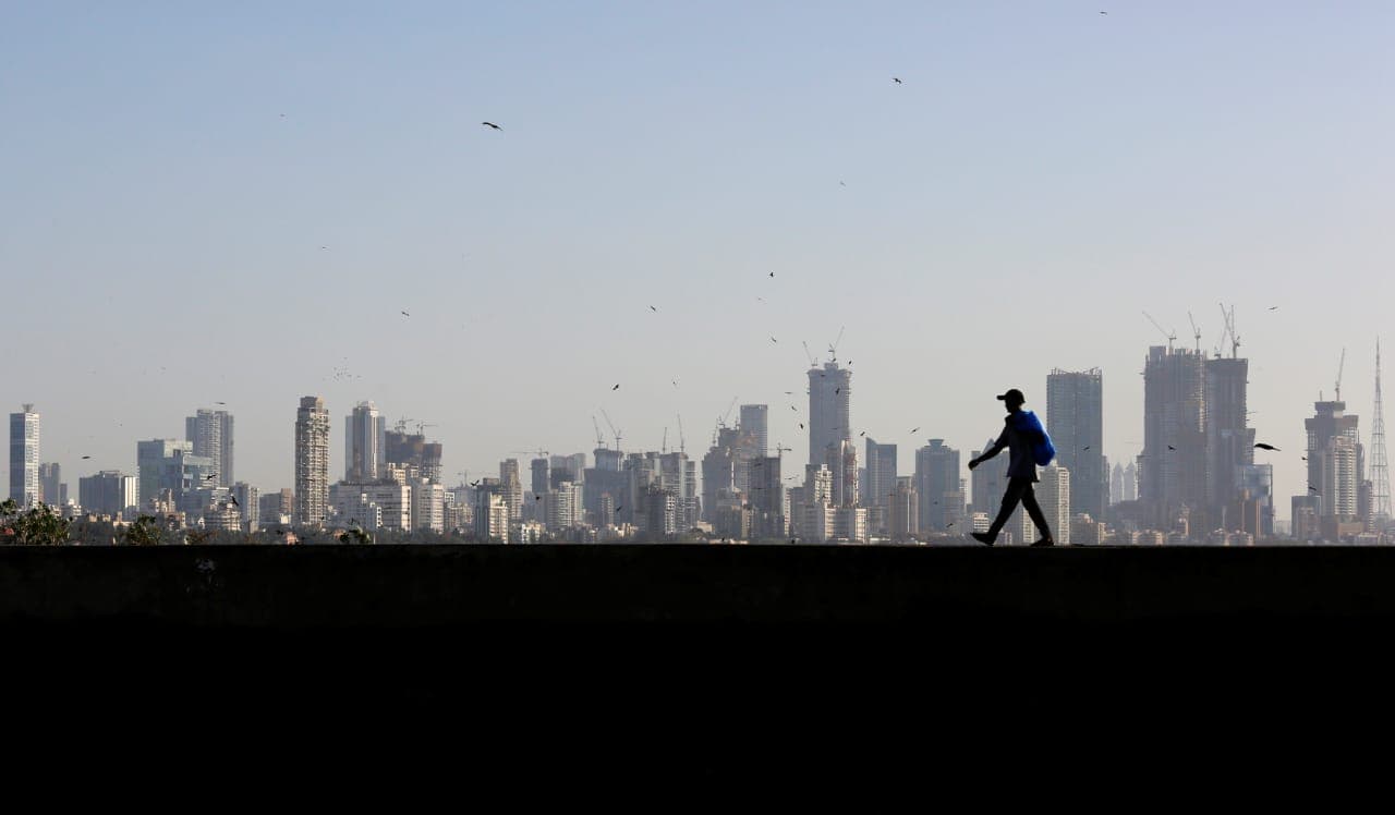 A man walks along a wall overlooking the central Mumbai's financial district skyline, India, March 9, 2017.