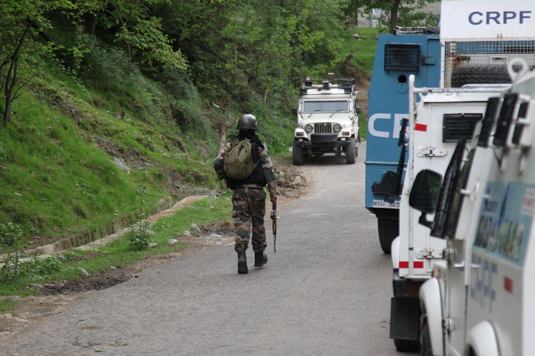 An Indian security force trooper moves past parked vehicles during a cordon and search operation, following an attack on tourists near Pahalgam, in Gudder village of south Kashmir's Kulgam district.
